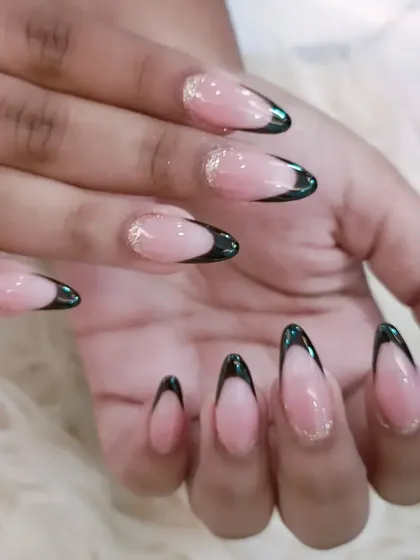 A sophisticated black French manicure on long almond nails. A fine line of gold glitter at the smile line adds a touch of unexpected glamour.