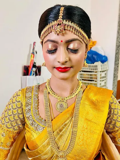 A close-up of the eye makeup, featuring a beautiful golden shimmer and a sharp, clean application. The bright red lip is a classic choice for a traditional bride.