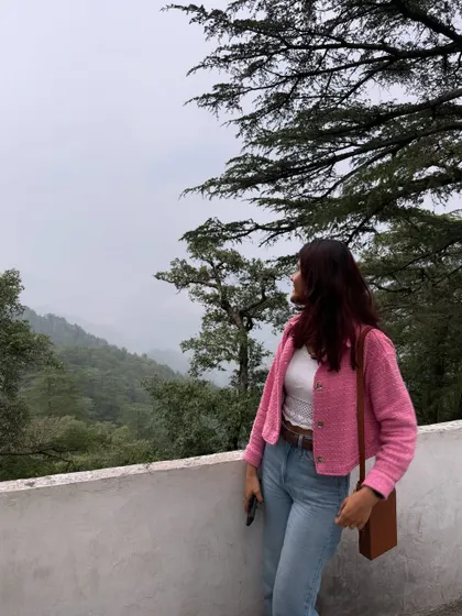 Taking in the misty mountain views. The pop of pink from my jacket adds a cheerful touch to the serene, green landscape. This is how you can use color to stand out in your travel photos.