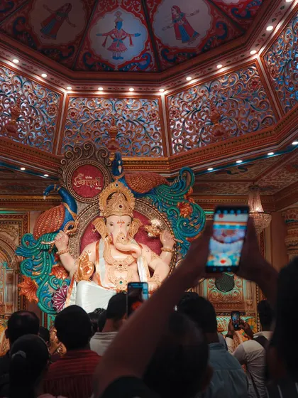 Worshippers gather to get a final glimpse of the beautifully decorated Ganpati idol inside a pandal. The intricate details on the idol and the ceiling are stunning.