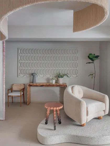 This vignette highlights the interplay of textures, from the soft, upholstered armchair to the rough-hewn wooden console and the intricate wall art. Each piece is placed on its own organic-shaped platform, elevating it from mere product to a piece of sculpture.