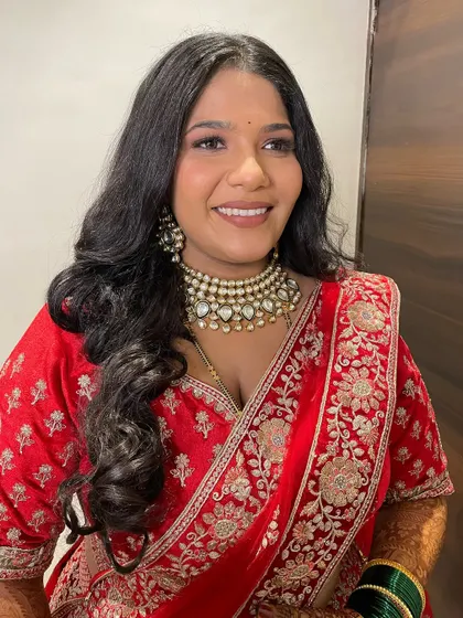 A stunning bride in a vibrant red lehenga. The makeup is kept soft and glowing to let the intricate outfit shine.