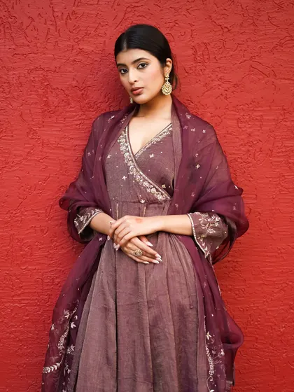 A classic portrait pose against a textured red background, making the deep color of the ethnic dress pop. The model's expression is serene, adding to the Sahiba vibe.