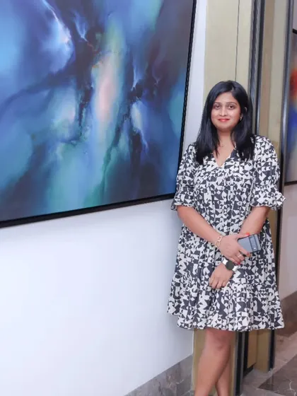 A visitor posing with a stunning blue abstract painting from the 'Mystic Mirage' exhibition.