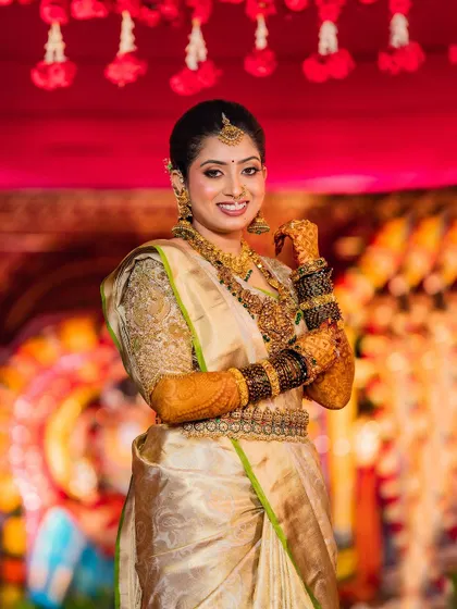 This bride glows in her gold Kanchivaram saree. The custom blouse with intricate embroidery adds a touch of luxury to her traditional muhurtham look.