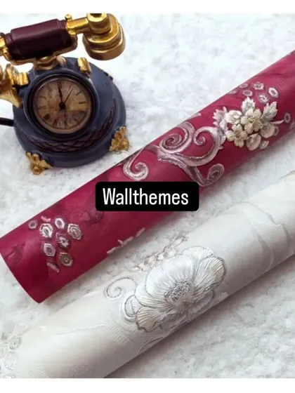 Two wallpaper rolls with a classic floral damask design, one in deep magenta and one in off-white, both with silver accents.