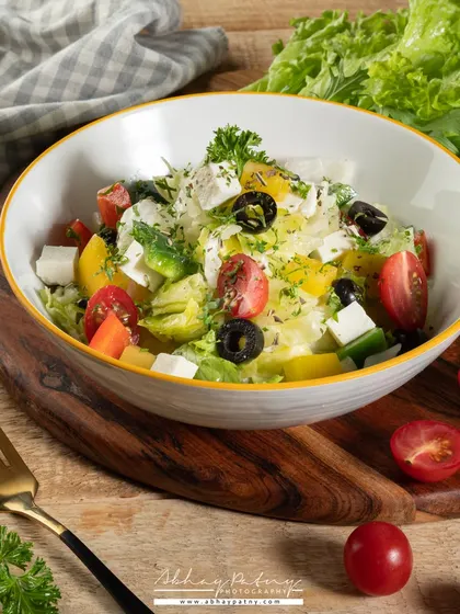 Another take on a fresh salad, this time with a focus on the variety of greens and colorful vegetables. The wooden board adds a touch of natural, rustic charm.