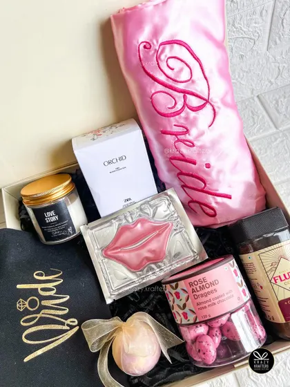This bride-to-be hamper includes a personalized pink satin 'Bride' robe, a 'Bride' t-shirt, and a selection of pampering treats.
