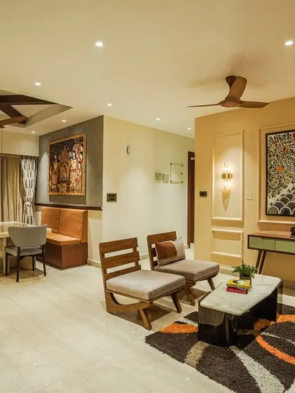 An open-plan living and dining area featuring a stunning Madhubani art piece, tan leather sofa, and a dining nook with bench seating.