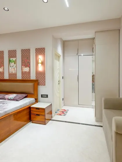This bedroom combines clean lines with artistic touches. The custom wooden bed and side table are complemented by a series of art panels above the headboard, adding a unique, personal element to the room.