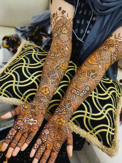 A beautiful bridal design with the name 'Issam' on the palm, surrounded by a dense floral pattern.