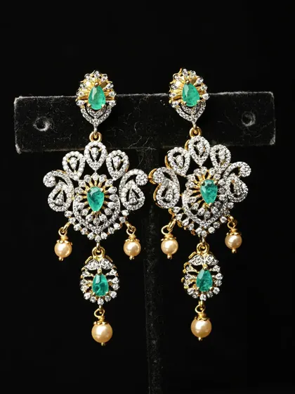 Exquisite chandelier earrings featuring intricate filigree work, American Diamonds, and emerald-colored stones. The design is finished with delicate pearl drops for added grace.