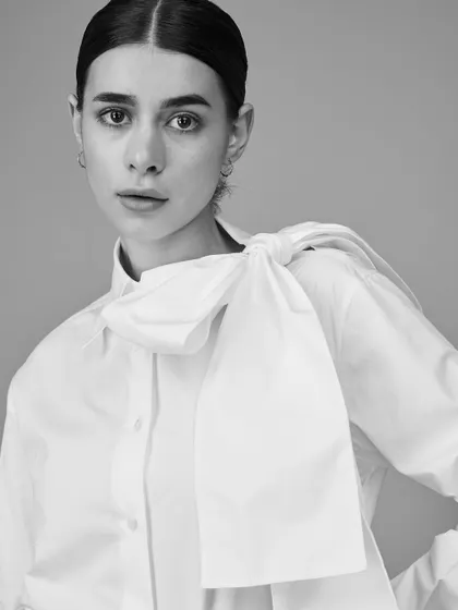 A modern and chic portrait with a focus on styling. The oversized bow adds a dramatic flair, while the clean lighting keeps the look sophisticated and fresh.