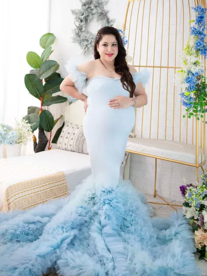 A full-length portrait showcasing the stunning light blue ruffled gown. The mother-to-be stands confidently, allowing the dress's dramatic train to be the star of the show.