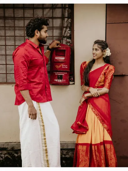 A couple shares a look by a classic red postbox in a village setting, adding a touch of nostalgia to their pre-wedding shoot.