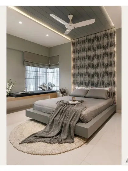 The bay window in this bedroom is transformed into a comfortable seating nook, perfect for reading or enjoying the view. The grey Roman blinds offer a clean, modern window treatment.