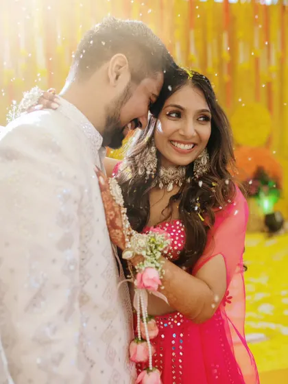 An intimate embrace between the couple during their Haldi, with flower petals falling around them.