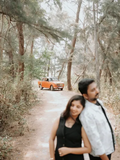 A quiet, romantic moment between the couple, with the vintage car in the background setting a nostalgic scene in the woods.
