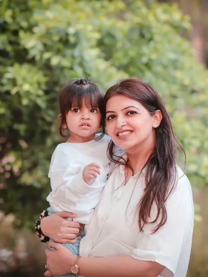 A beautiful mother-daughter portrait taken outdoors, with a soft, natural background.