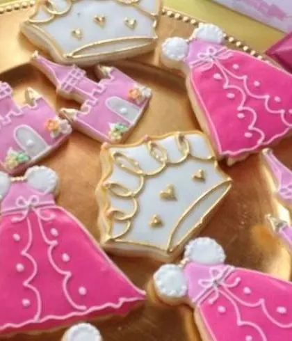 Custom-designed cookies are a perfect party favor. These feature intricate icing designs of princess dresses and castles, adding a sweet and memorable touch to a royal celebration.