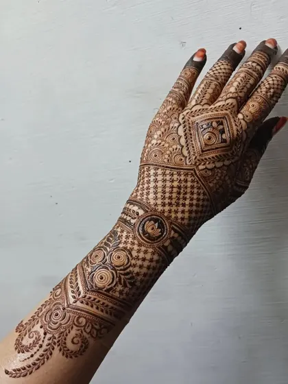 A complete view of an intricate back-hand design that extends up the arm. The pattern flows from a central geometric element, using a mix of grids and traditional motifs for a stunning effect.