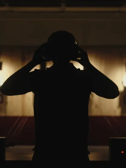The silhouette of a shooter getting in position. This dramatic still captures the intense focus required in the sport.