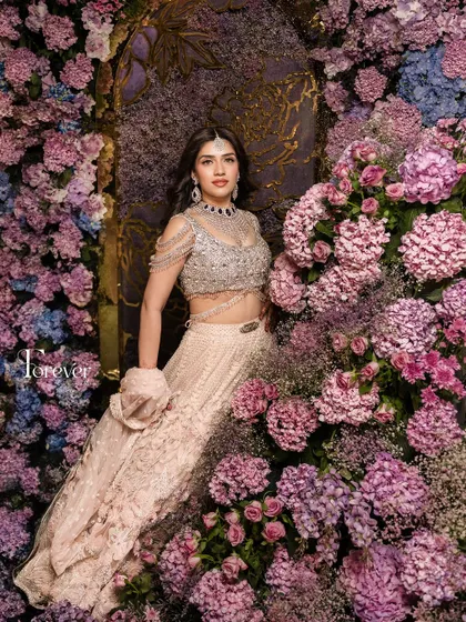 Mahima looking like a princess in a sea of flowers. Her makeup is soft and radiant, enhancing her natural beauty and creating a truly magical bridal portrait.