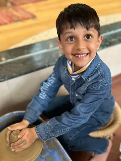 The look of pure delight. This boy's upward glance while working the clay captures the wonder and excitement of learning a new, hands-on skill.