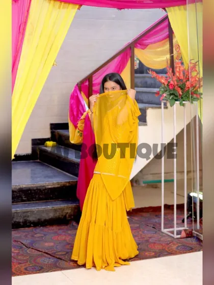 A client looking lovely in a yellow sharara suit, perfect for a Haldi ceremony. The simple design allows for heavy jewelry and floral accessories.