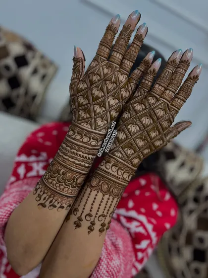 An elegant back-of-hand design for an engagement, featuring a delicate jaal pattern with hanging bead details.