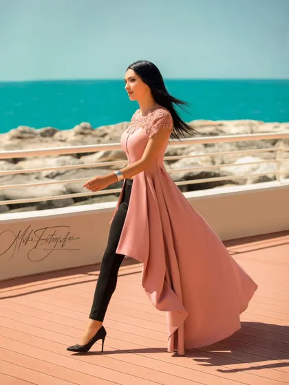 A dynamic walking shot on a boardwalk in Dubai, with the ocean in the background. The movement in the model's dress and hair creates a feeling of freedom and effortless style.