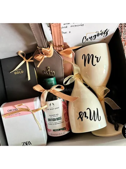 A stylish couple's hamper with 'Mr & Mrs' wine glasses, personalized luggage tags, and luxury bath products from The Body Shop.