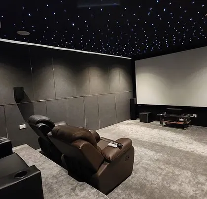 A luxury home cinema delivered to Dr. Uwaraj in Madurai, featuring a dark, minimalist design with a starlit ceiling and comfortable leather recliners.