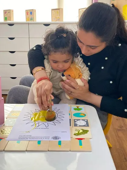 A teacher gently guides a child through a coloring activity. This one-on-one attention helps children feel secure and confident as they settle into the school environment.
