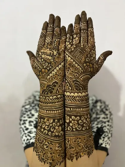 A classic pose showing the beautiful symmetry of this engagement henna. The design includes floral bands and leafy vines for a complete look.