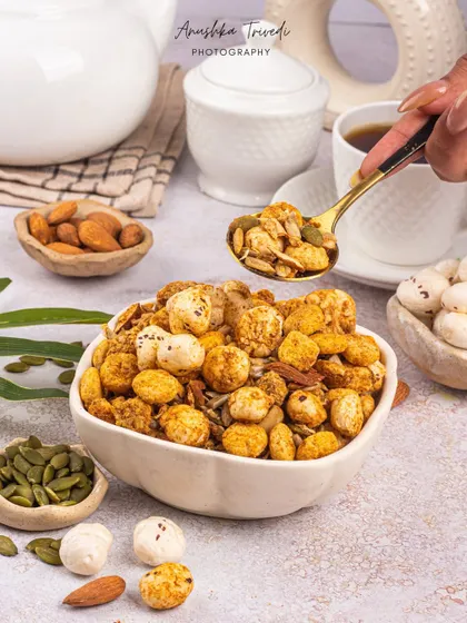 An action shot of a spoonful of the makhana mix, highlighting the variety of nuts and seeds in the product.