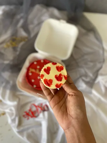 A close-up of a heart-themed cupcake, part of a matching set with a red bento cake.