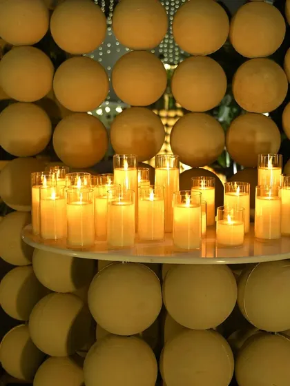 A modern and artistic installation of candles set against a backdrop of uniform spheres. This element adds a contemporary touch to the otherwise rustic and earthy decor.