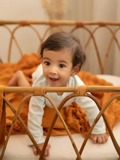 Peek-a-boo! The pure joy of a baby who has just learned to pull themselves up, with a smile that could light up any room.