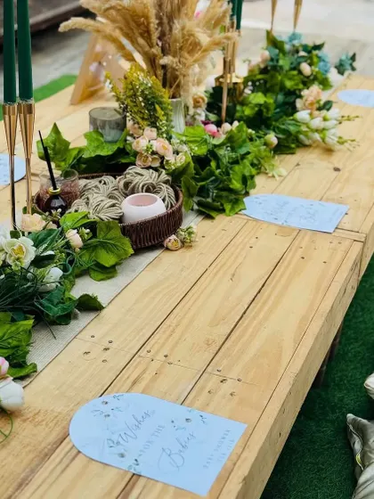 We designed a low-seating picnic-style table for a relaxed and intimate boho baby shower. The wooden table is adorned with a green garland and personalized place cards.