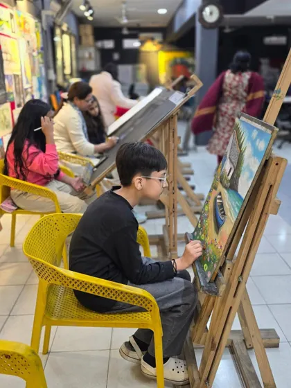 A young student fully engaged in creating a landscape with oil pastels during one of our classes.