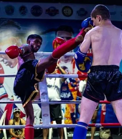 A perfectly timed teep, or push kick, to control distance during an international Muay Thai bout. This is a fundamental and effective technique.