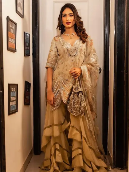 A full-length view of a glamorous look for celebrity Aneri Vajani. The makeup features a bold red lip and defined eyes, paired with voluminous waves for a festive and celebratory feel.