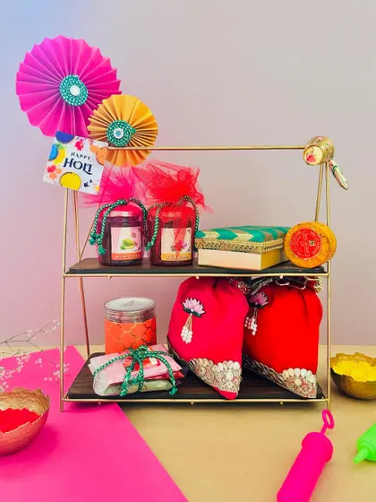 A two-tiered stand makes for a grand Holi gift. I've arranged jars of treats, colorful potlis, and other festive items on it, creating an impressive and generous hamper.