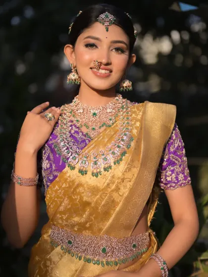 A regal look featuring a golden Kanchi tissue saree paired with a rich purple hand-embroidered blouse. The contrast is both bold and beautiful.
