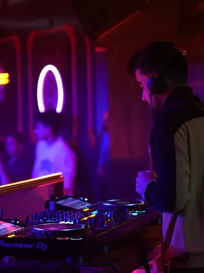A side view of me focused on the Pioneer DJ decks, with neon lights in the background. This shot highlights the professional setup I bring to every gig.