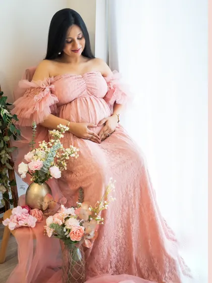 A gentle smile in a beautiful setting. This close-up in the pink lace gown highlights the mother's happy glow, surrounded by soft florals.