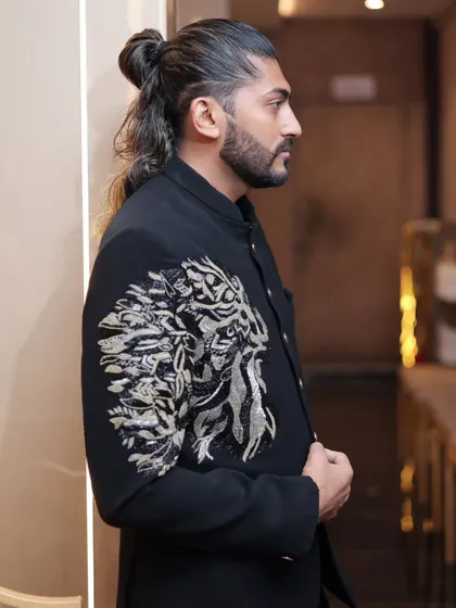 A side profile showcasing the detailed lion embroidery on the sleeve and shoulder of our black Jodhpuri suit. It’s a true statement piece.