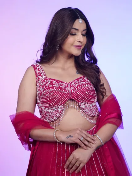 A detailed shot of the hot pink lehenga's blouse. The intricate silver and pearl beadwork with dangling tassels is what makes this piece a true showstopper.