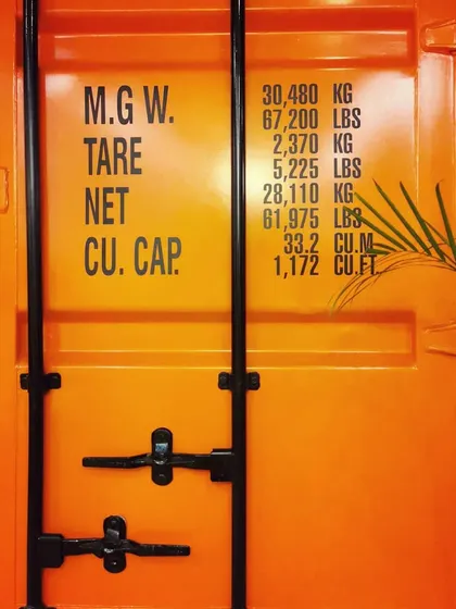 The original markings on the shipping container door, which we preserved to maintain the authenticity and story of the repurposed object.